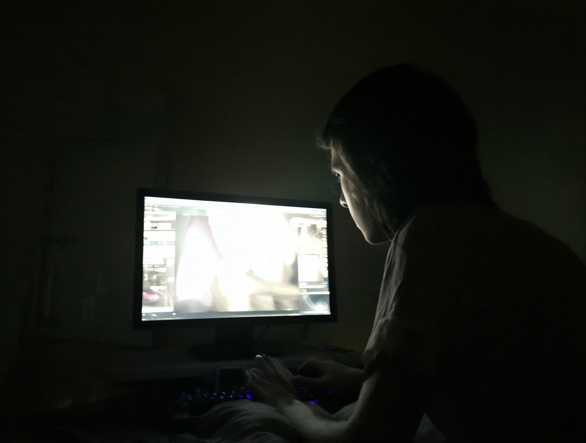 Hombre aislado con una pantalla brillante en una habitación oscura