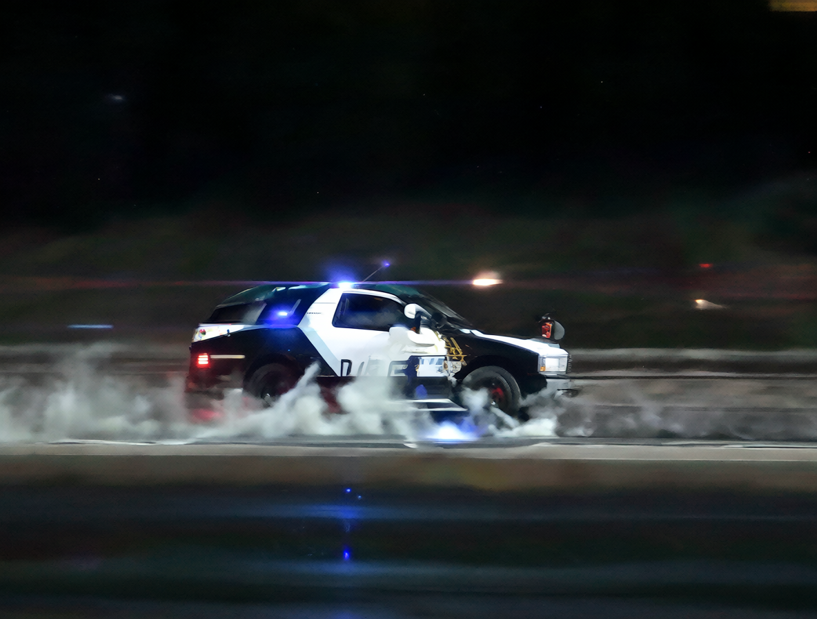 Un coche de policía persiguiendo en una carretera con luces azules parpadeando y humo de neumáticos