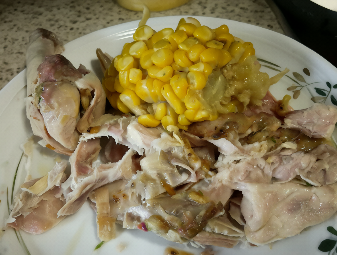 Plato con pollo y choclo cocido sobre una encimera a temperatura ambiente.