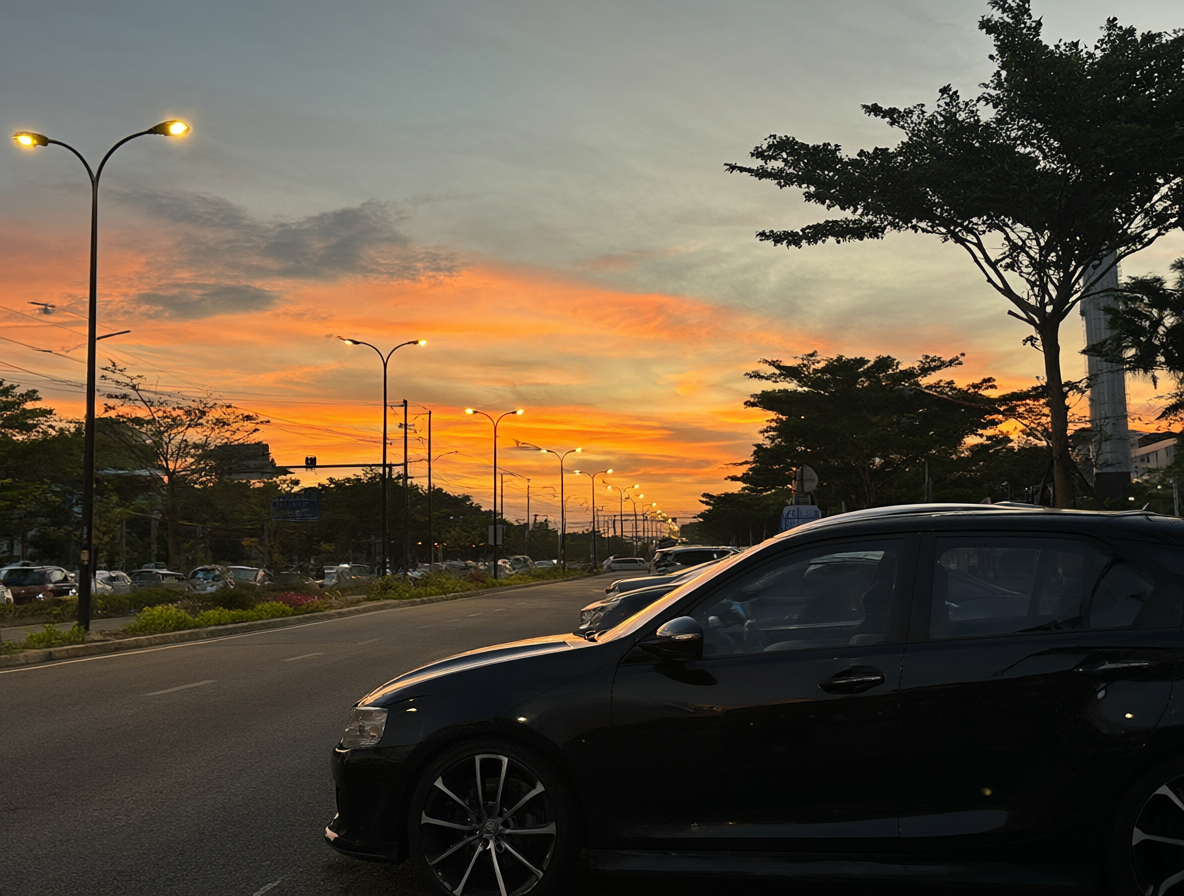 Vista de un estacionamiento vacío al atardecer con un coche detenido en la penumbra.