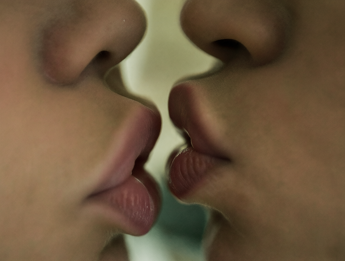 Close-up of two lips kissing passionately in soft lighting.