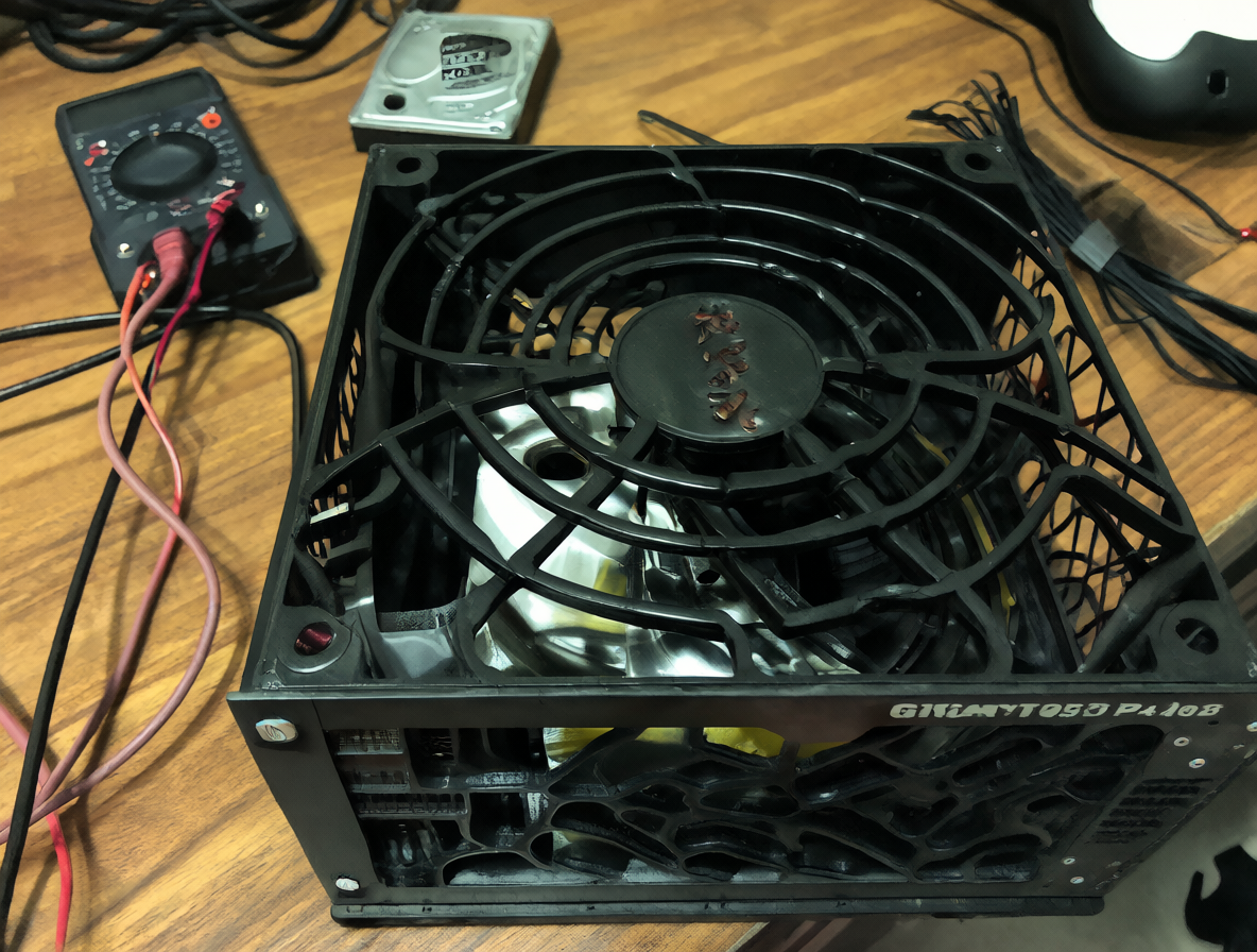Una unidad de poder negra con todos los cables negros sobre una mesa de madera.