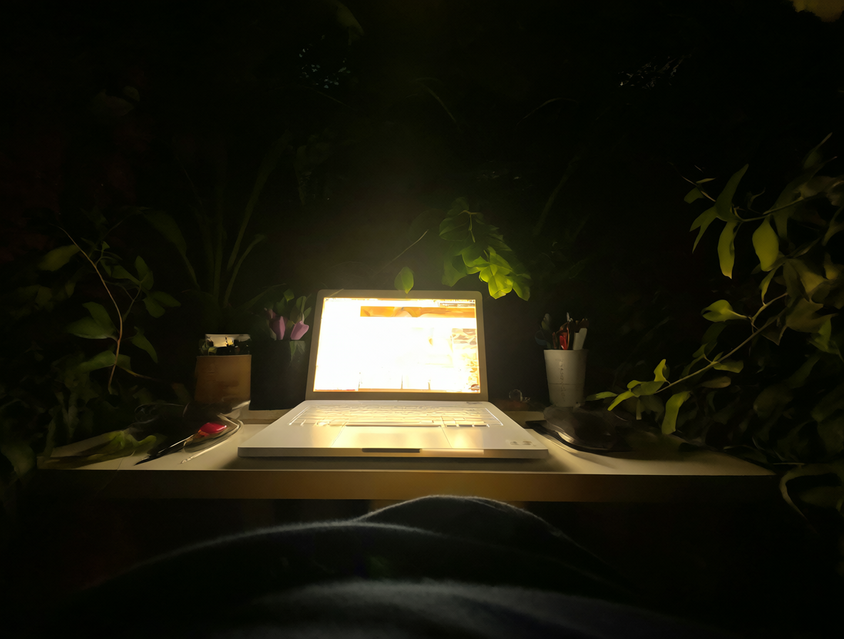 Programador trabajando en un escritorio iluminado por una laptop en la oscuridad