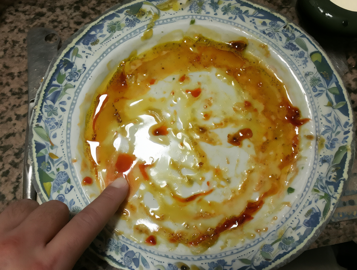 Plato vacío con residuos y una persona limpiando sus dedos después de comer.