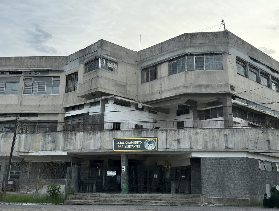 Vista exterior de una prisión de hormigón con ventanas de seguridad bajo un cielo nublado.