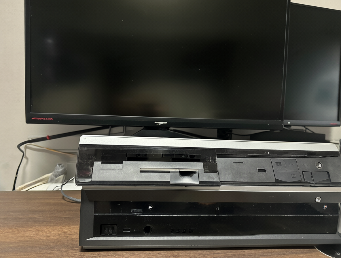 Una cámara de grabación VHS moderna junto a una pantalla LCD estándar sobre una superficie limpia.