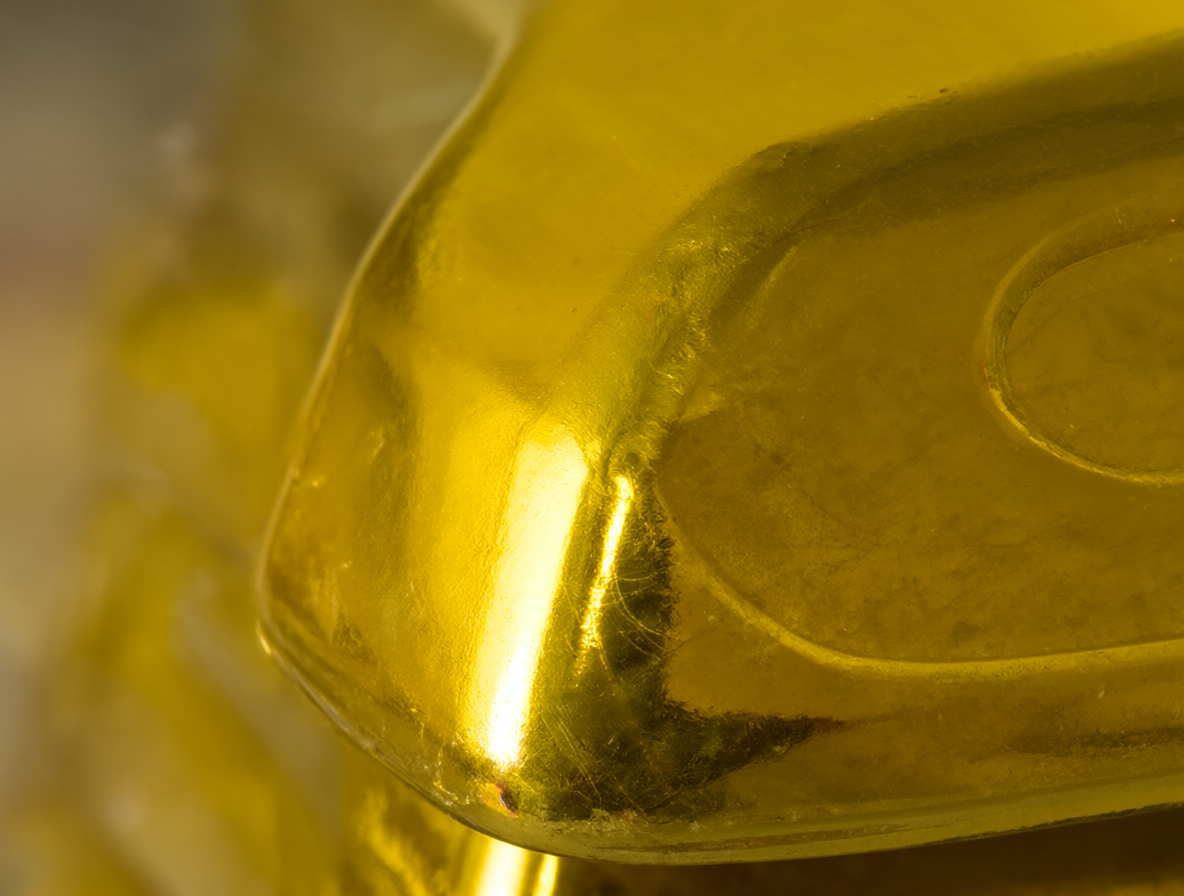 Un primer plano detallado de un lingote de oro brillante y rectangular sobre un fondo desenfocado.