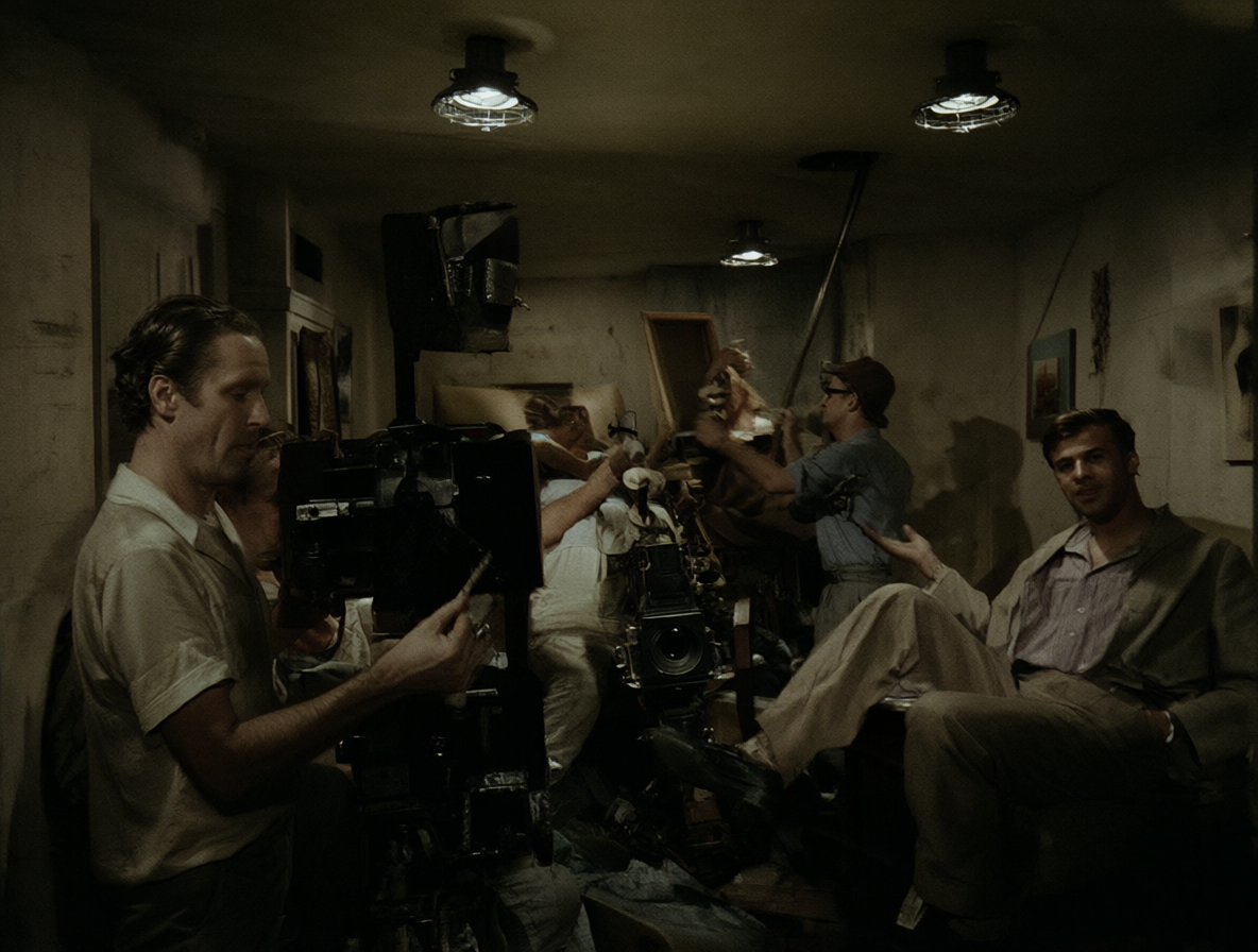 Vista del set de filmación con técnicos moviendo muebles alrededor de una cámara fija en los años 40.