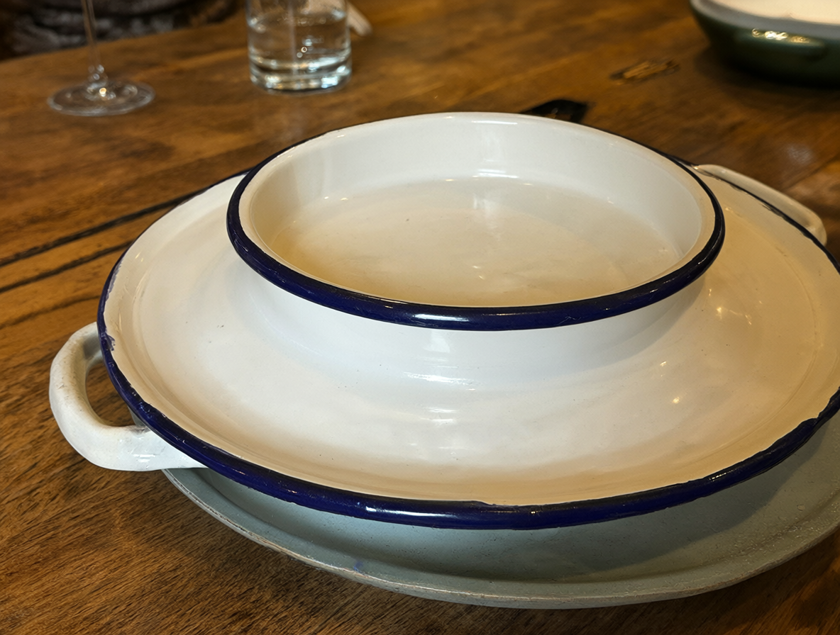 Primer plano de un plato de cocina enlozado sobre una superficie de madera.