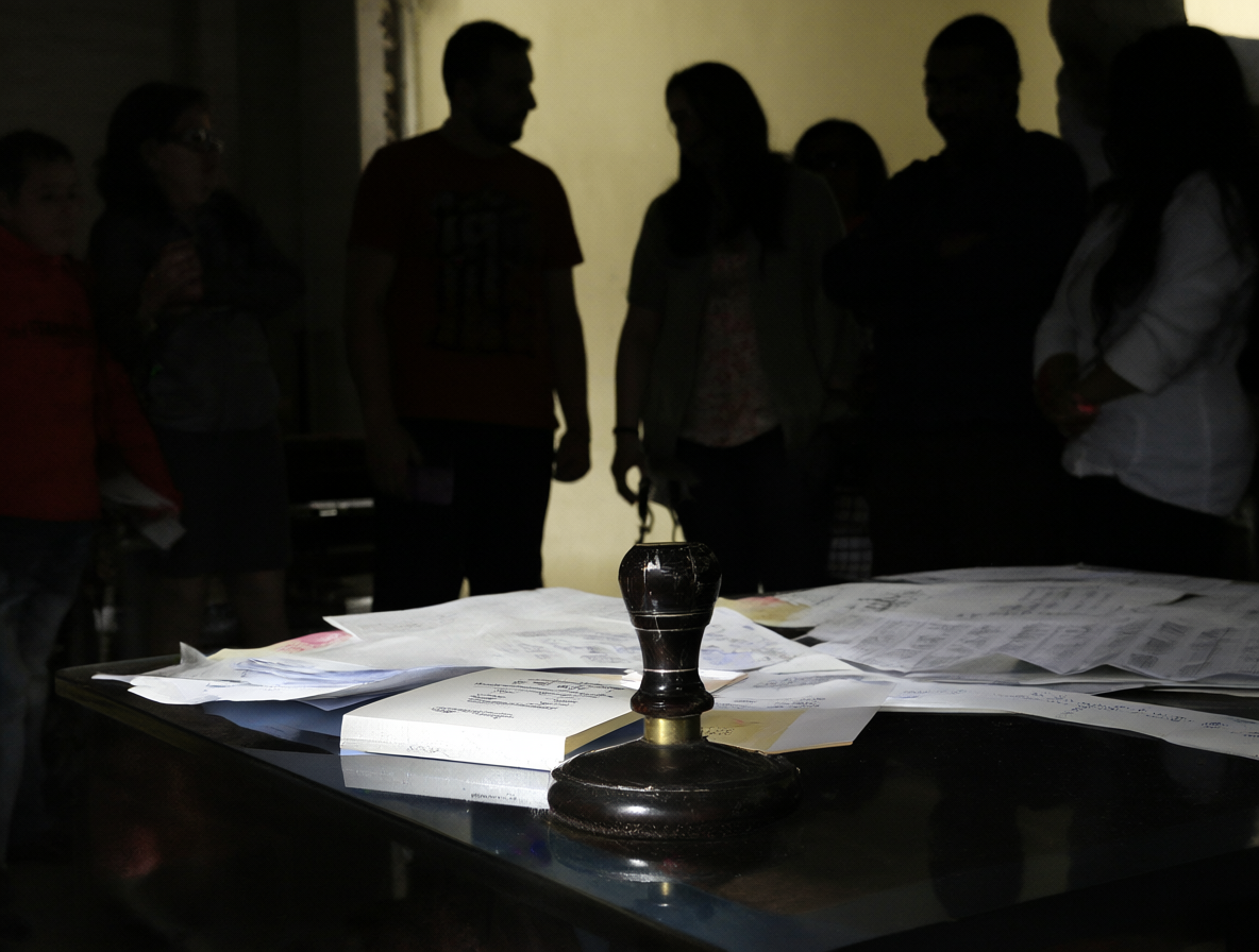 Escritorio de notaría con documentos y siluetas de personas