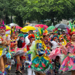 Vista de un evento al aire libre bajo la lluvia con gente disfrutando a pesar del clima