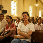 Retrato de una mujer llamada Claudina sentada en un banco dentro de una iglesia evangélica, rodeada por otros miembros de la congregación.