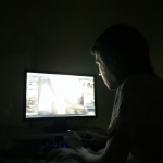 Hombre aislado con una pantalla brillante en una habitación oscura