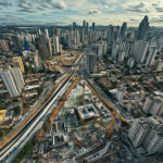 Vista aérea de un edificio residencial aislado rodeado por maquinaria pesada y construcción masiva en el centro de la ciudad.