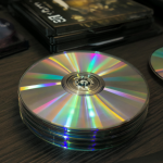 Una pila ordenada de discos Blu-ray de alta calidad sobre un escritorio de madera oscura, junto con estuches tipo jewel case.