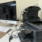 Varias impresoras idénticas conectadas a un ordenador en una oficina moderna.