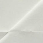 Vista macro de un documento escaneado con una esquina anterior doblada que ahora está completamente plana, mostrando una textura uniforme sin reflejos ni arrugas.