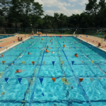 Vista general de una piscina con varios nadadores usando traje de baño adecuado