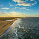 Sunny beach at golden hour with a rippling sea breeze