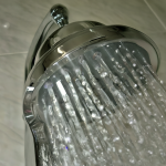 Ducha de acero inoxidable con agua fluyendo.
