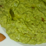 Plato de palta molida con una zona amarga resaltada y una almendra al lado