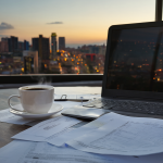 Vista clara de un moderno escritorio con una laptop abierta y una taza de café frente a una ventana con vista a la ciudad chilena, simbolizando el inicio de un emprendimiento tecnológico.
