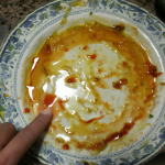 Plato vacío con residuos y una persona limpiando sus dedos después de comer.