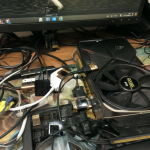 Close-up view of the messy cable connections between a modern GPU and an old VGA monitor on a desk.