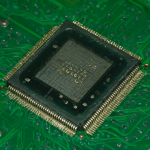 Imagen macro de un chip electrónico H5TQ2G63FFR sobre una placa de circuito impreso verde con componentes electrónicos.