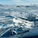 Crucero blanco navegando por hielo, personal médico inspecciona el muelle.