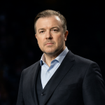 Retrato de Ricky Gervais mirando con determinación en un escenario oscuro, ignorando la presión externa.