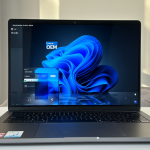 Un laptop moderno sobre un escritorio limpio, con la pantalla mostrando una interfaz de Windows 11 Home en modo S y una etiqueta flotante que dice 'Licencia OEM'.