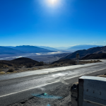Vista del desierto de California con asfalto brillando al calor extremo y una estación meteorológica.