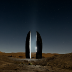 Monolito negro en un desierto bajo estrellas
