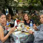 Mujer mayor comiendo con familia al aire libre