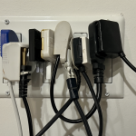 Vista de cerca de un tomacorriente saturado con múltiples adaptadores y cables.