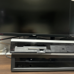Una cámara de grabación VHS moderna junto a una pantalla LCD estándar sobre una superficie limpia.