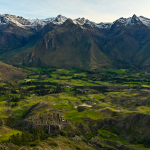 Vista aérea de las montañas de los Andes al amanecer con valles verdes y llamas pastando.