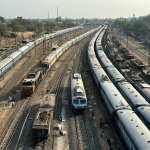 Vista de múltiples trenes indios compartiendo infraestructura con personas en el entorno cercano.