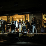 Exterior de una tienda de ropa en Chile siendo robada por un grupo armado bajo la luz de la noche.