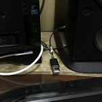 A view of an LG TV connected via optical cable to an external USB sound card, alongside a desktop PC and Logitech Z607 speakers.