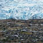 Vista aérea de un glaciar en Chile con casas vulnerables cerca, mostrando el derretimiento acelerado y las comunidades humanas expuestas.