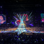 Ana Torroja del grupo Mecano cantando frente a una gran multitud con luces de escenario brillantes
