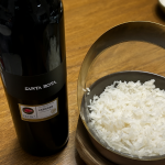 Bottle of Santa Rita red wine next to a bowl of white rice on wood