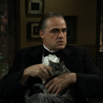 Vista del personaje Don Vito Corleone sosteniendo un gato gris en su oficina