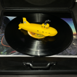 Caja de edición Super Deluxe abierta con varios discos y un submarino amarillo en primer plano