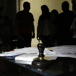 Escritorio de notaría con documentos y siluetas de personas