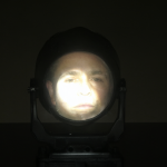 Foco PAR brillante apuntando a la cara del espectador en un salón oscuro.