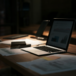 Freelancer revisando datos de marketing en un portátil con iluminación tenue