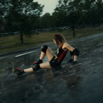 Una patinadora con un traje revelador cayendo en la lluvia sobre una colina empinada.